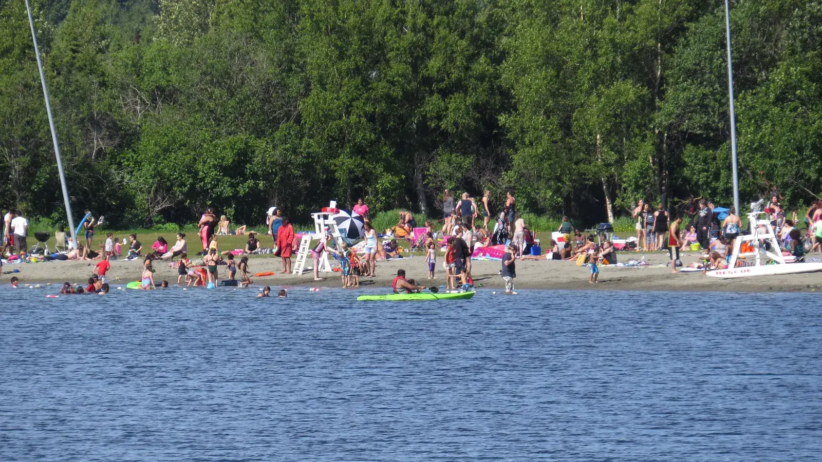 Swimmers and a kayak at the beach at Jewel Lake Park on a summer day