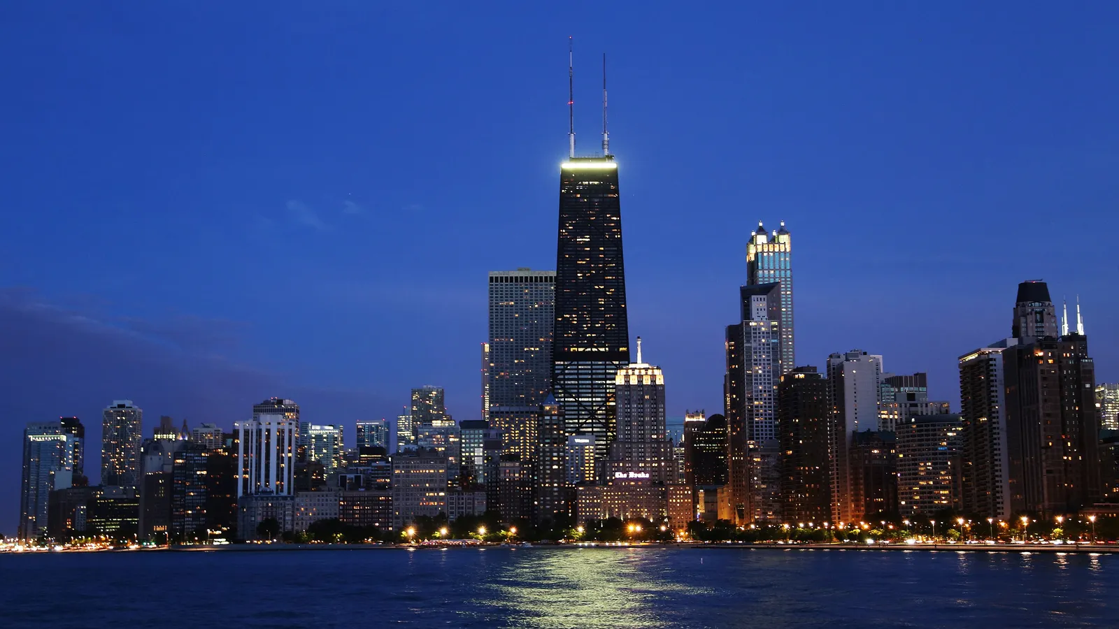 The Chicago skyline lit up at dusk over Lake Michigan from North Avenue Beach