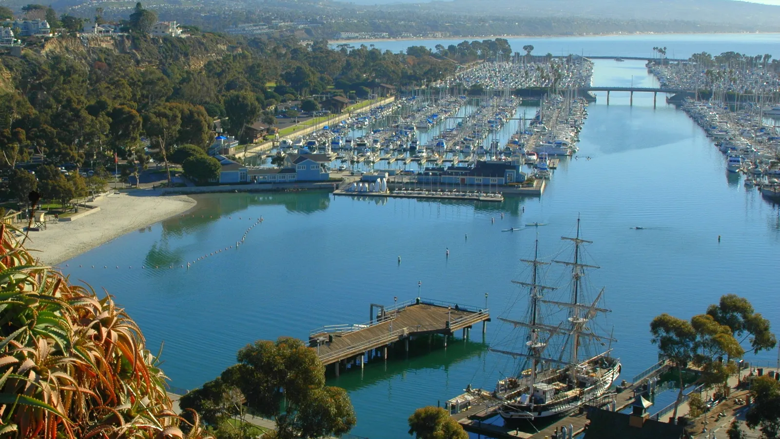 Dana Point Harbor's west basin from above, with a tall ship moored at the Ocean Institute