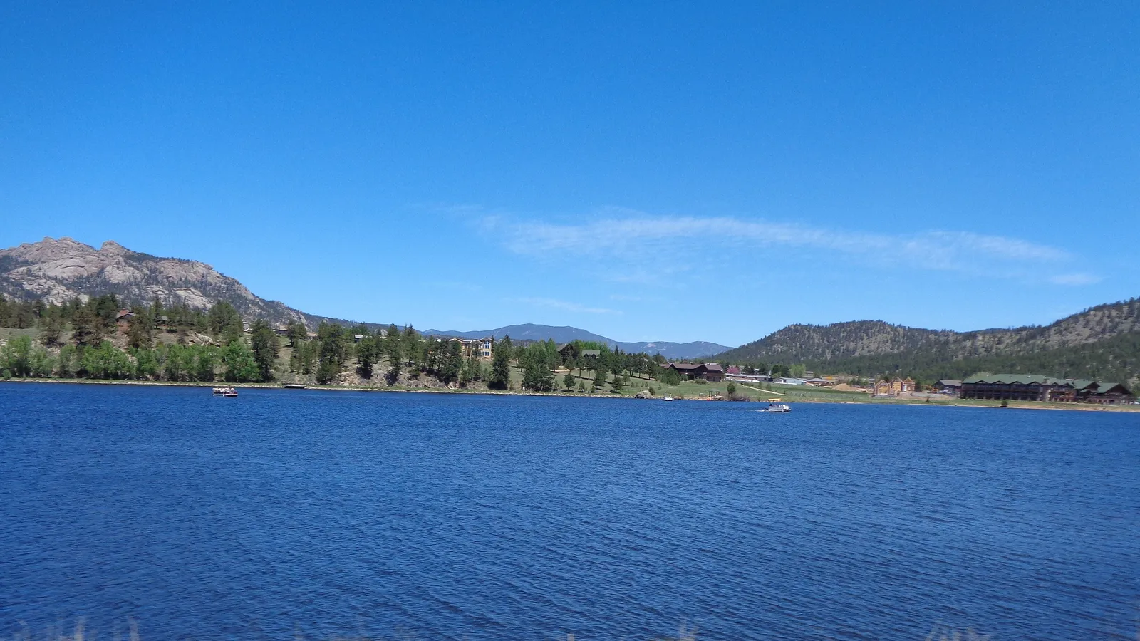Deep blue water on Lake Estes, with wooded hills and rocky peaks behind