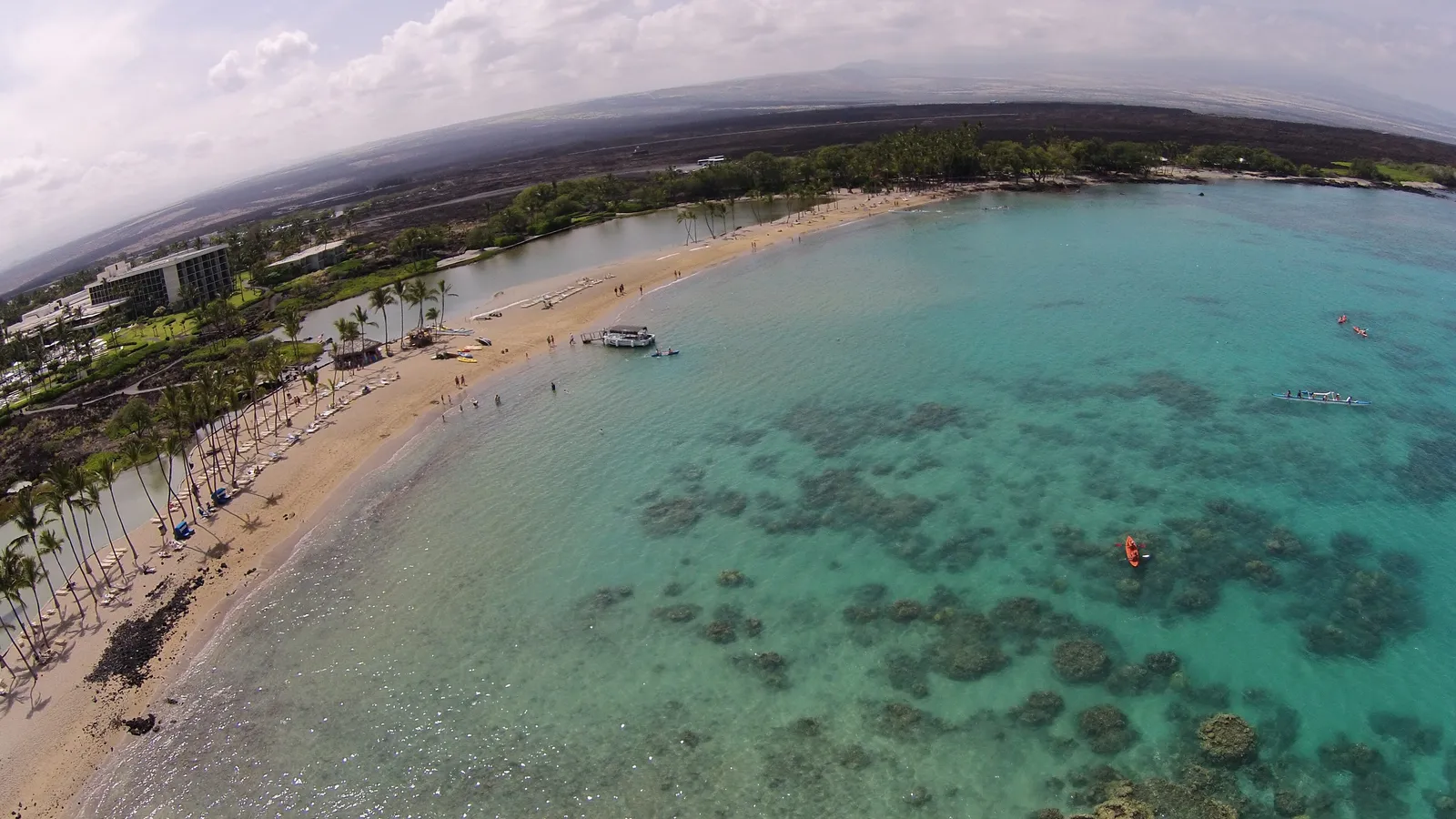 Aerial view of the palm-lined beach and clear water of ʻAnaehoʻomalu Bay