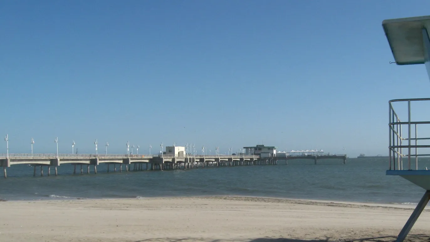 Belmont Veterans Memorial Pier seen from the sand in Belmont Shore, with flat water behind the breakwater