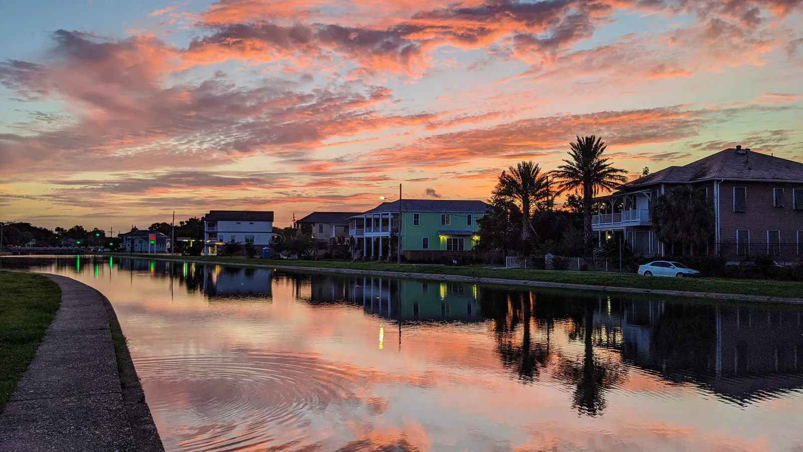Sunrise reflected in Bayou St. John, with houses along the bank