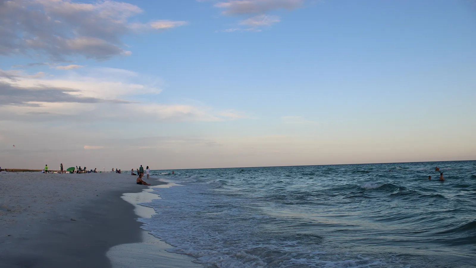 Clear green water and white sand at Navarre Beach in the evening