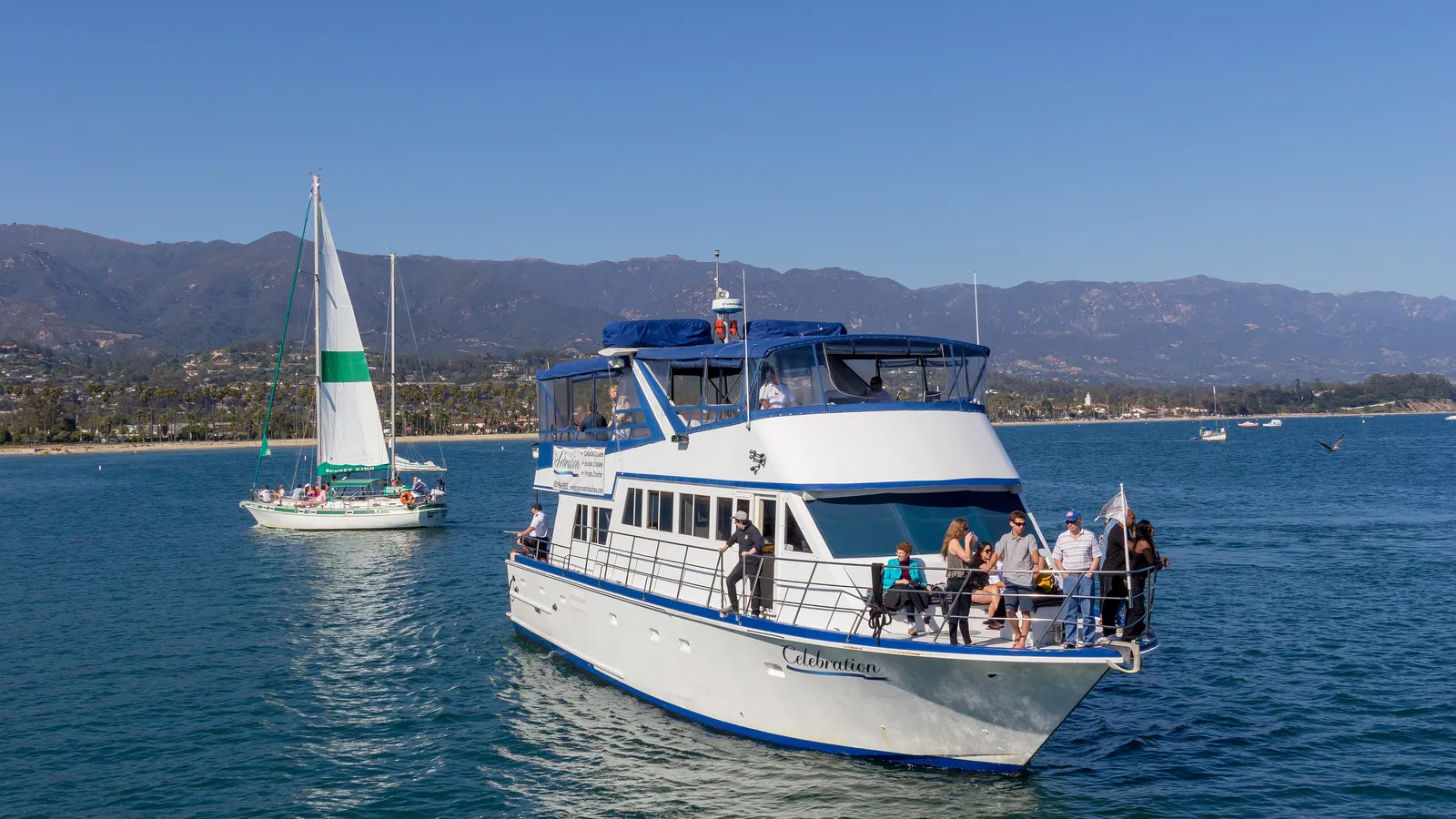 A sailboat and a tour boat off Santa Barbara, with the mountains behind the city
