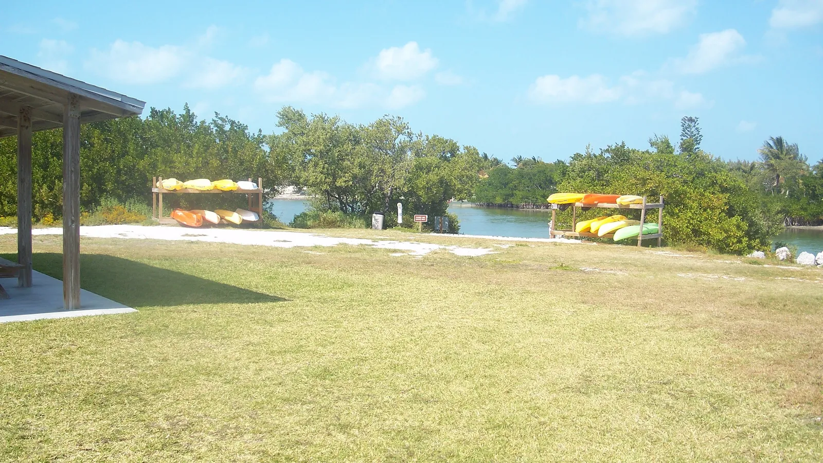Racks of rental kayaks beside a calm mangrove-lined lagoon at Curry Hammock State Park