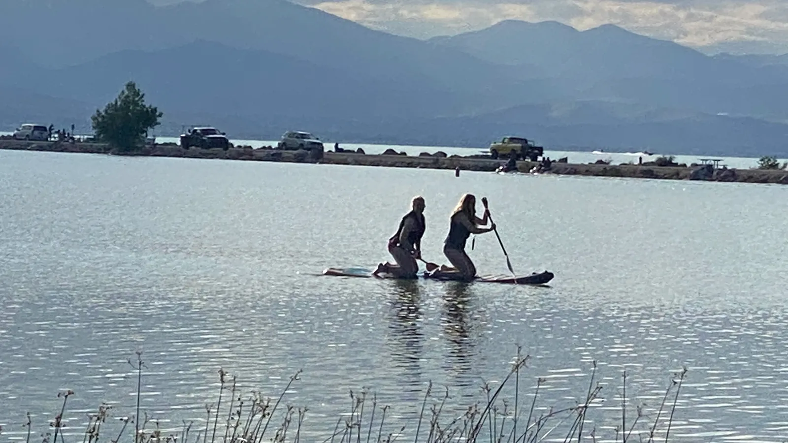 Two paddlers kneeling on a paddle board in the marina at Utah Lake State Park