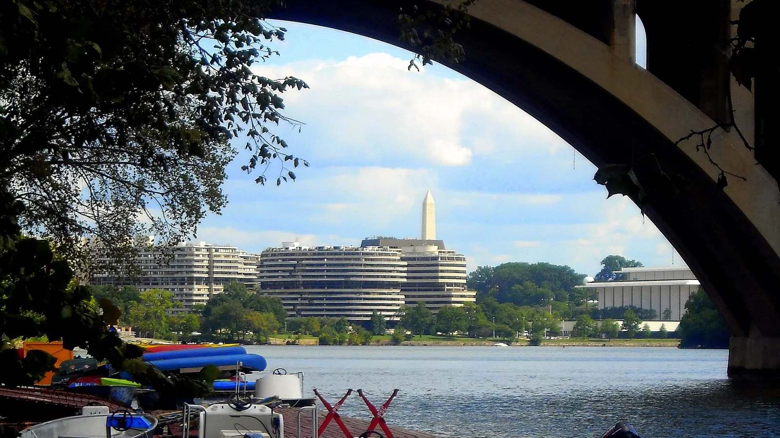 Rental boats on the dock under Key Bridge, with the Watergate, the Kennedy Center and the Washington Monument across the Potomac