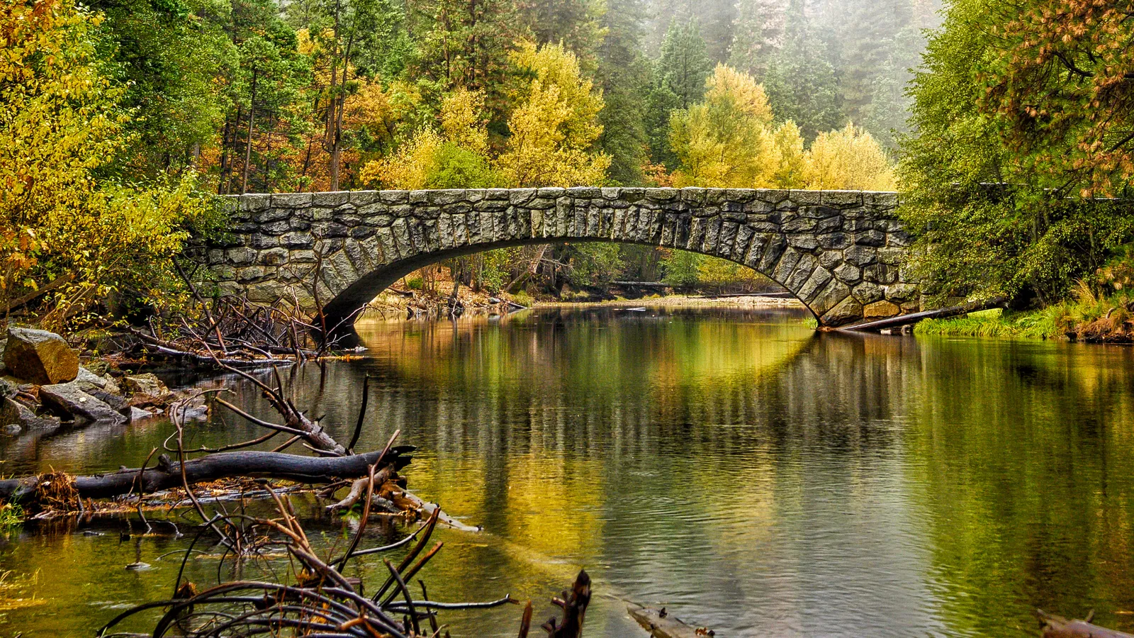 Stoneman Bridge over a calm stretch of the Merced River in fall colors